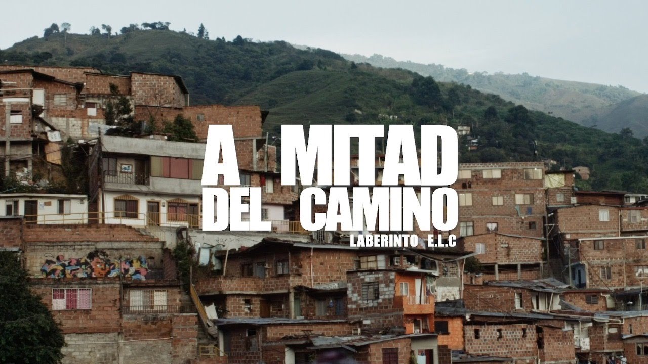 Imagem de um morro com diversas construções e o texto A Mitad Del Camino